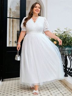 a woman in a white dress is standing outside