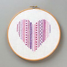 a cross - stitch heart is shown on a white background with pink and purple stripes