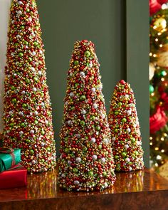 three christmas trees made out of candy are sitting on a table in front of a christmas tree