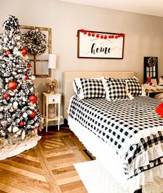 a bedroom decorated for christmas with black and white bedding, plaid comforter, red ornaments and a tree