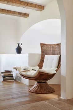 a wicker chair sitting on top of a hard wood floor next to a vase