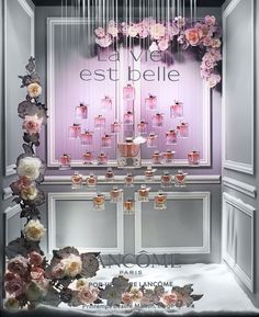 the entrance to a perfume store with pink flowers and chandeliers hanging from the ceiling