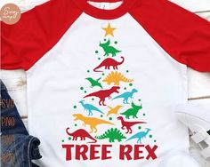 a red and white shirt with dinosaur christmas tree on it, sitting next to jeans