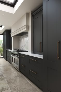 a large kitchen with black cabinets and marble counter tops on both sides, along with a skylight above the stove