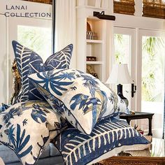 blue and white pillows stacked on top of each other in front of a large mirror