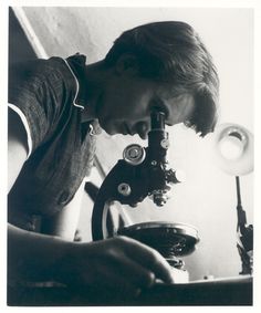 an old photo of a boy looking through a microscope