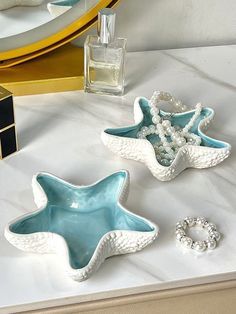 three starfish shaped dishes sitting on top of a counter next to a bottle of perfume