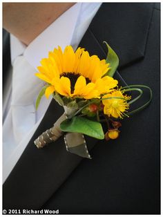 a boutonniere with sunflowers and greenery on the lapel