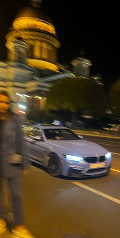 a man riding a skateboard down a street next to a white car in front of a building