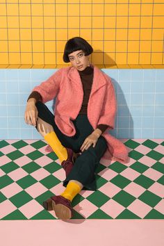 a woman sitting on top of a tiled floor next to a yellow and blue wall