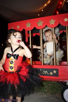 two children dressed up as clowns in front of a fake circus train at night