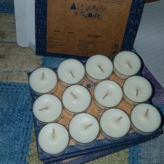 many white candles are sitting in a cardboard box