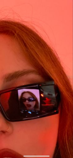 a woman with red hair and glasses is taking a selfie in her cell phone