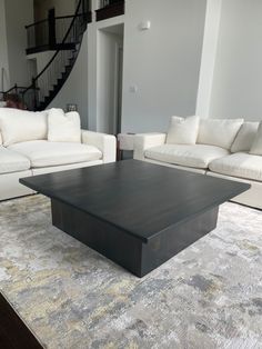 a living room with white couches and a black coffee table in the center area