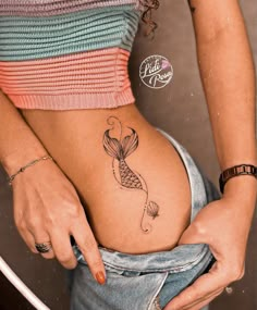 a woman with a fish tattoo on her stomach is holding onto the side of her belly