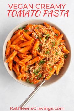 vegan creamy tomato pasta in a white bowl with a serving spoon on the side