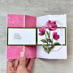 a hand holding a card with pink flowers on it