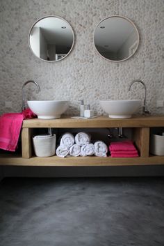 there are two sinks in the bathroom with towels and cups on the shelf next to them