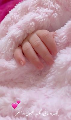 a close up of a baby's hand wrapped in a pink blanket with hearts