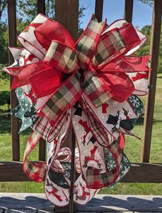 a red, white and green christmas deco bow on a metal stand in front of a wooden fence