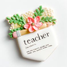 a cookie shaped like a teacher's bag with flowers and leaves on it that says, teacher