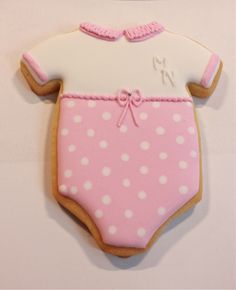 a decorated cookie in the shape of a baby's bodysuit with pink and white polka dots