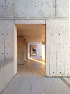 an empty room with wooden floors and white concrete walls that are partially covered in sunlight