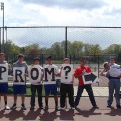 a group of young men holding up signs in front of a fence with the word prom written on them