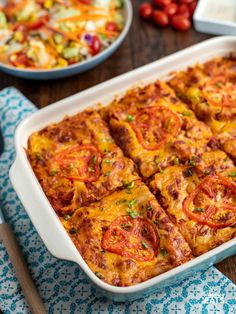 a casserole dish with tomatoes, cheese and other toppings on the side