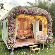 an outdoor living area with pink flowers on the walls and white furniture in the grass