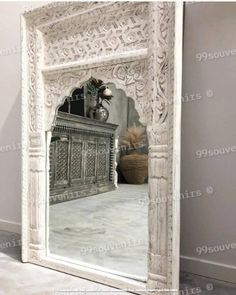 a white mirror sitting on top of a floor next to a vase and potted plant