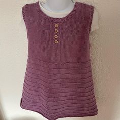 a purple knitted top with buttons on the front and back, hanging from a hook