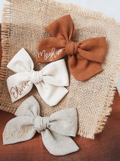 three small bows with names on them sitting on a burlock cloth pillow that says, mr and mrs