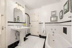 a bathroom with black and white tile flooring and wall mounted mirrors above the bathtub