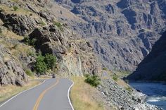 an empty road in the mountains near a river