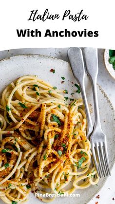 pasta with parmesan cheese and herbs on a white plate next to a fork