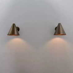 two lamps are on the wall next to each other in front of a white wall