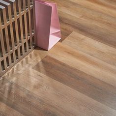 a pink shopping bag sitting next to a wooden radiator on top of a hard wood floor