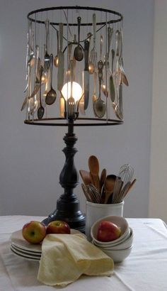 a lamp that is on top of a table with some fruit and spoons in it