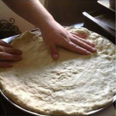 a person is kneading dough on top of a pizza pan with their hands