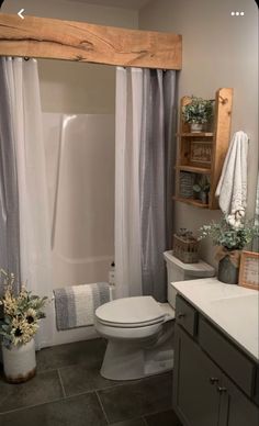 a white toilet sitting in a bathroom next to a sink and bathtub under a wooden beam