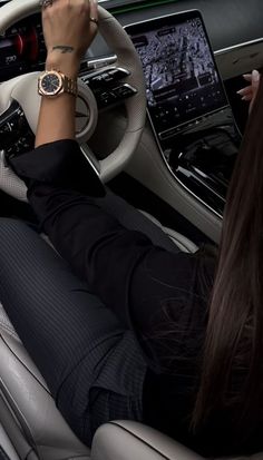 a woman sitting in the driver's seat of a car with her hands on the steering wheel