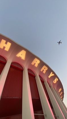 an airplane is flying over the harry's airport sign on top of a building