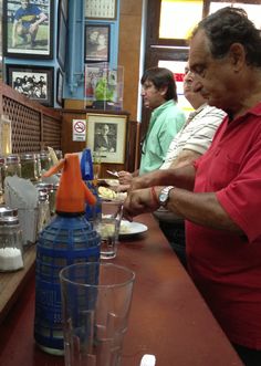 an older man is serving himself food at the restaurant table with other people in the background