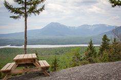 a wooden picnic table sitting on top of a mountain