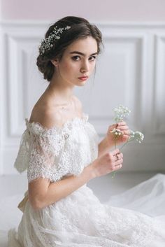 a woman in a white dress holding a flower and wearing a tiara on her head