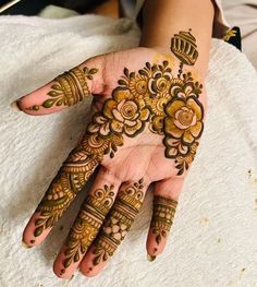 a woman's hand with henna tattoos on it and flowers in the middle