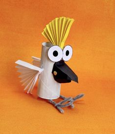 a bird made out of toilet paper on an orange background with eyes and beaks