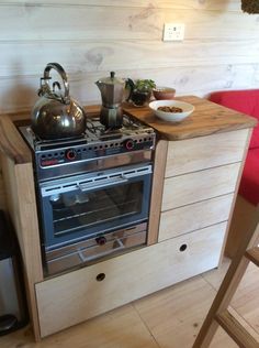 a stove top oven sitting inside of a kitchen next to a wooden counter and chair