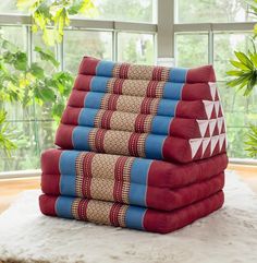 a stack of red and blue towels sitting on top of a white rug in front of a window